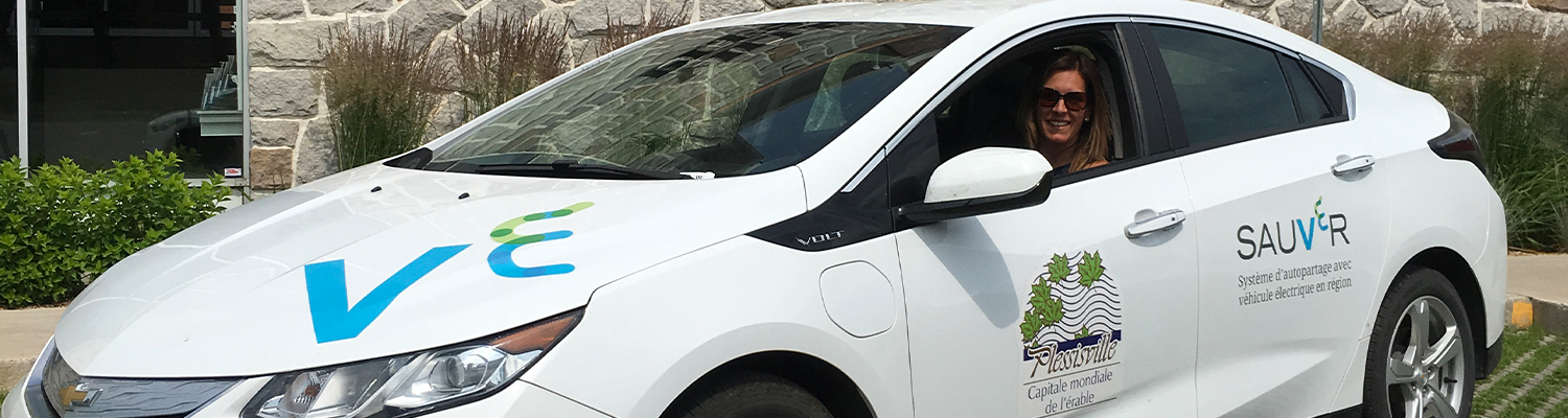 A Plessisville resident smiling, sitting in one of the new electric vehicles