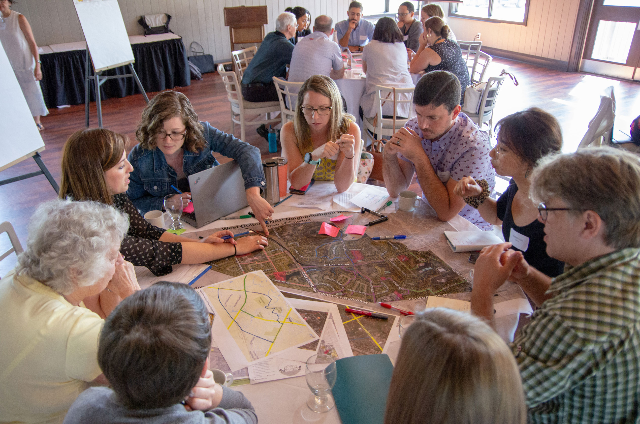 Group of people sit at a round table looking over maps. 