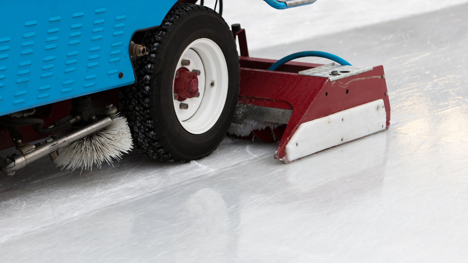 A close up of a Zamboni crossing an indoor ice rink 