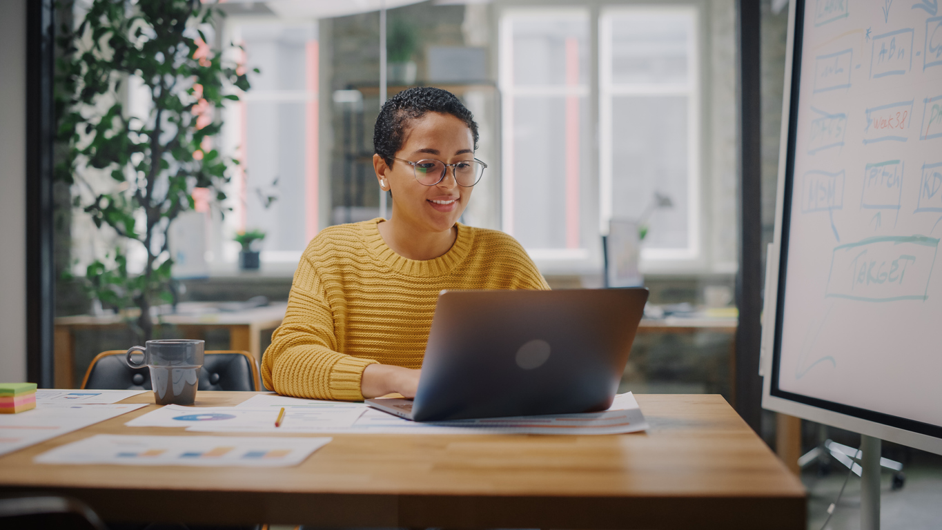 Portrait of young Latin marketing specialist in glasses working on laptop computer