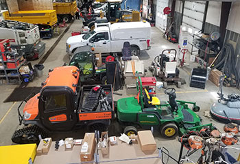 A number of vehicles and other equipment parked inside a large garage-type building, with some people visible in the background.