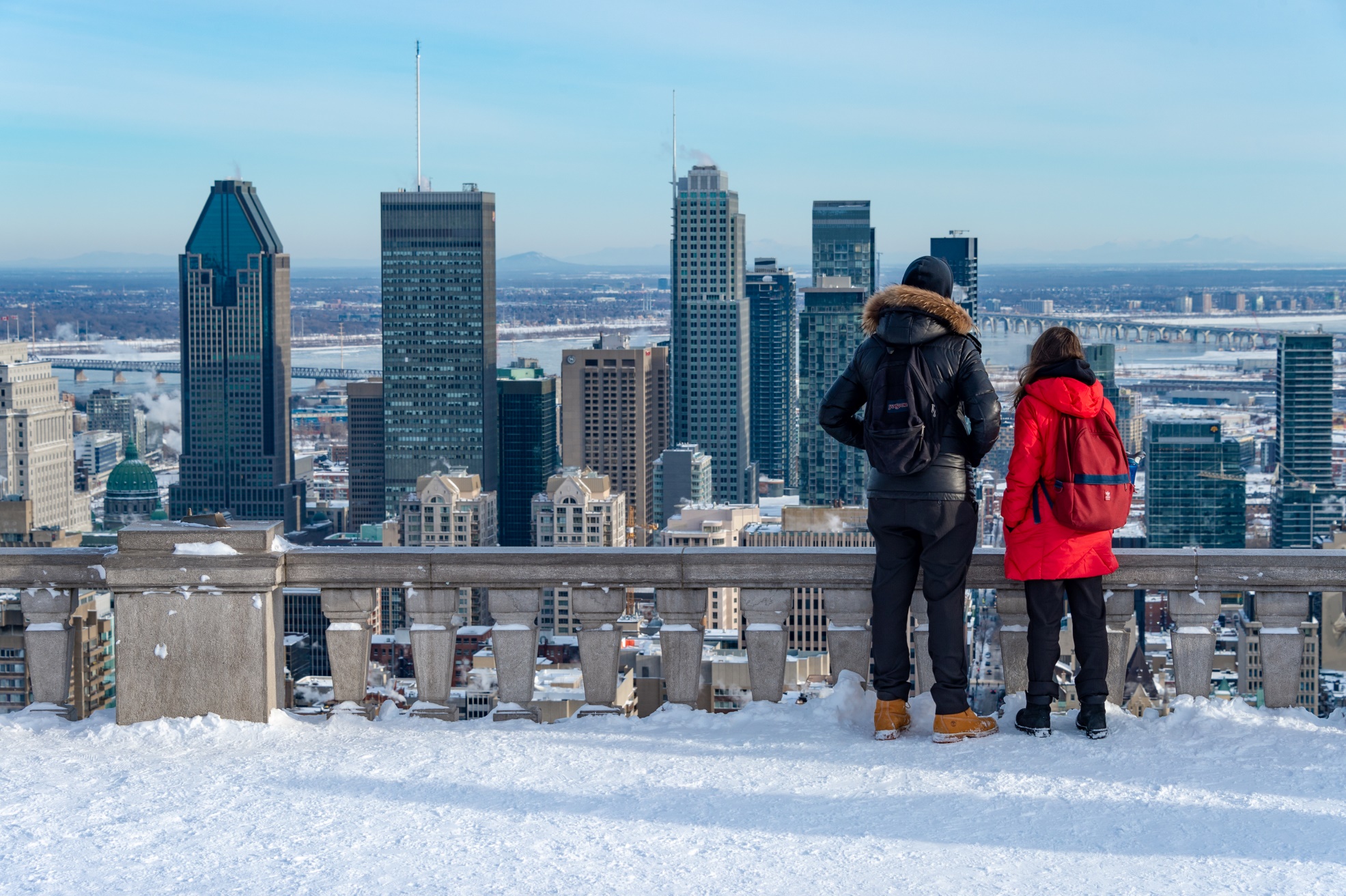 Two people look out over a snowy Montreal skyline