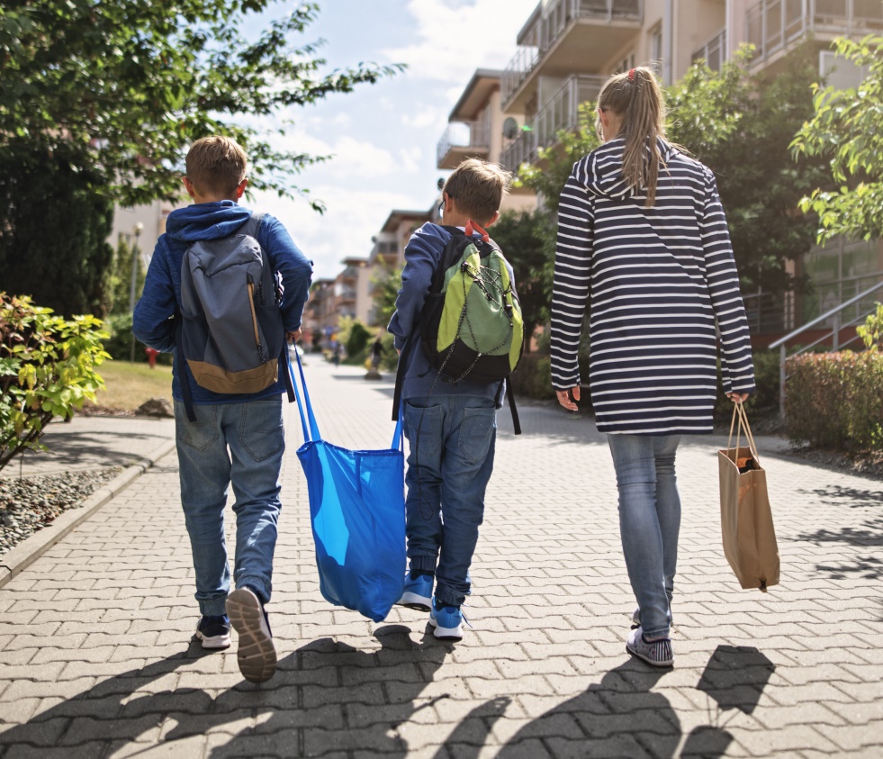 A family walks down the street in a sustainable neighborhood on a warm sunny day