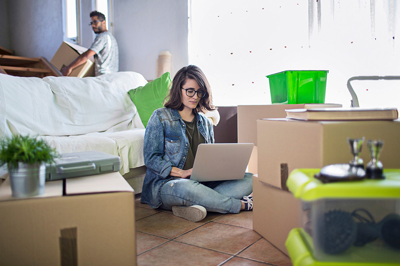 Woman on laptop surrounded by moving boxes