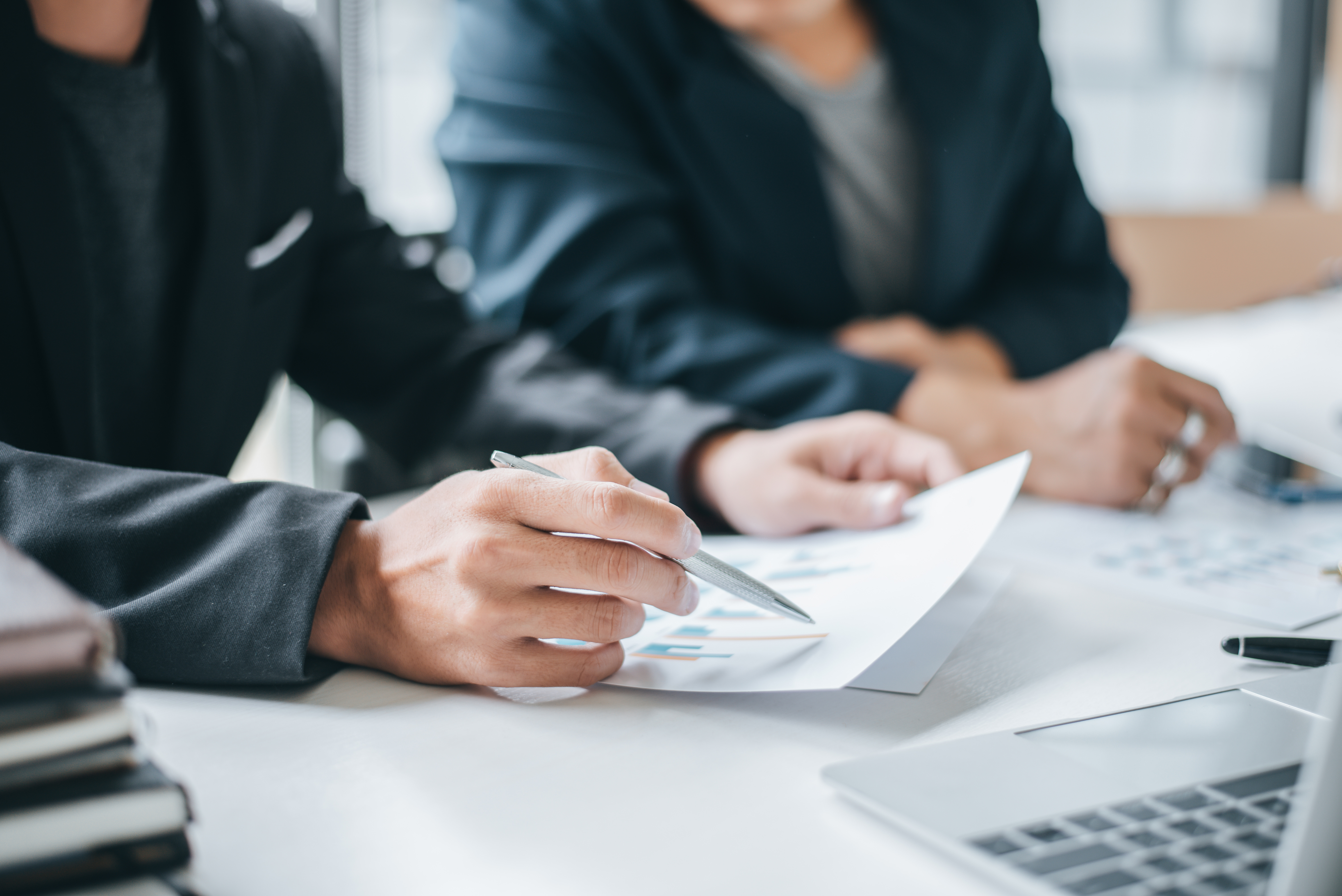 Businessperson using a calculator in a bright, white room. 