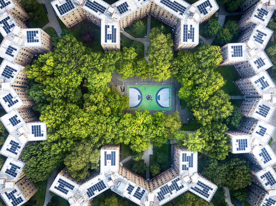 An aerial view of a green park surrounded by buildings with solar panels on their roofs