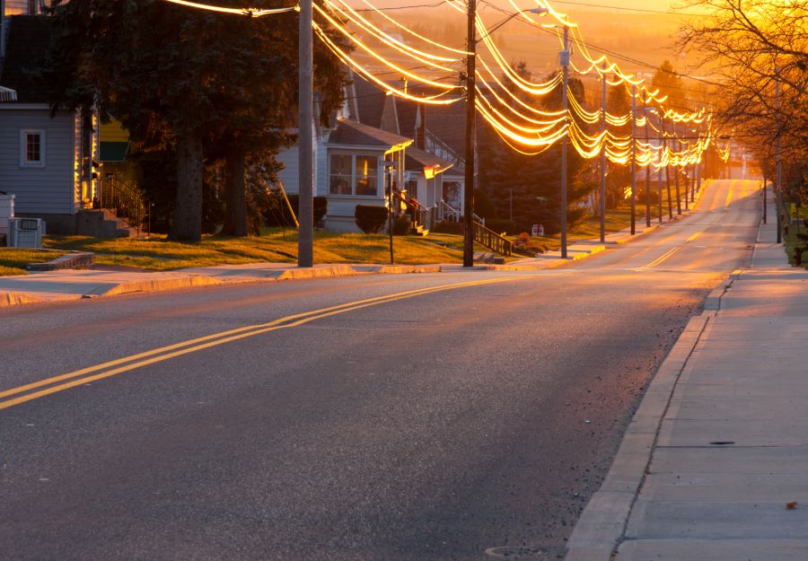 Neighbourhood street lined with electric wires and poles. Sunset