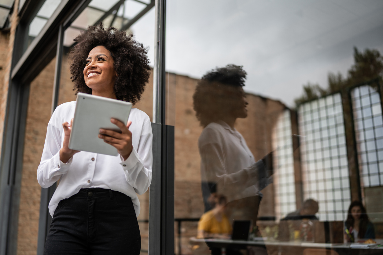 Businesswoman looking away and using a digital tablet in an office. 