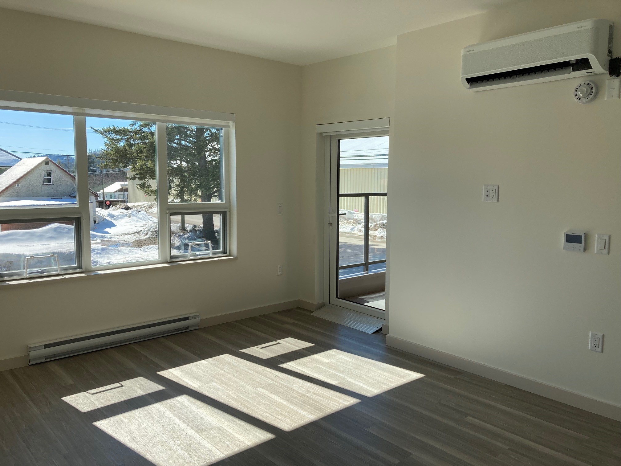 An empty living space with windows and a door in the Rossland Yards affordable housing building in Rossland, BC