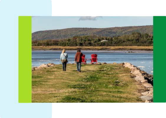 2 people walking towards chairs kept by the water