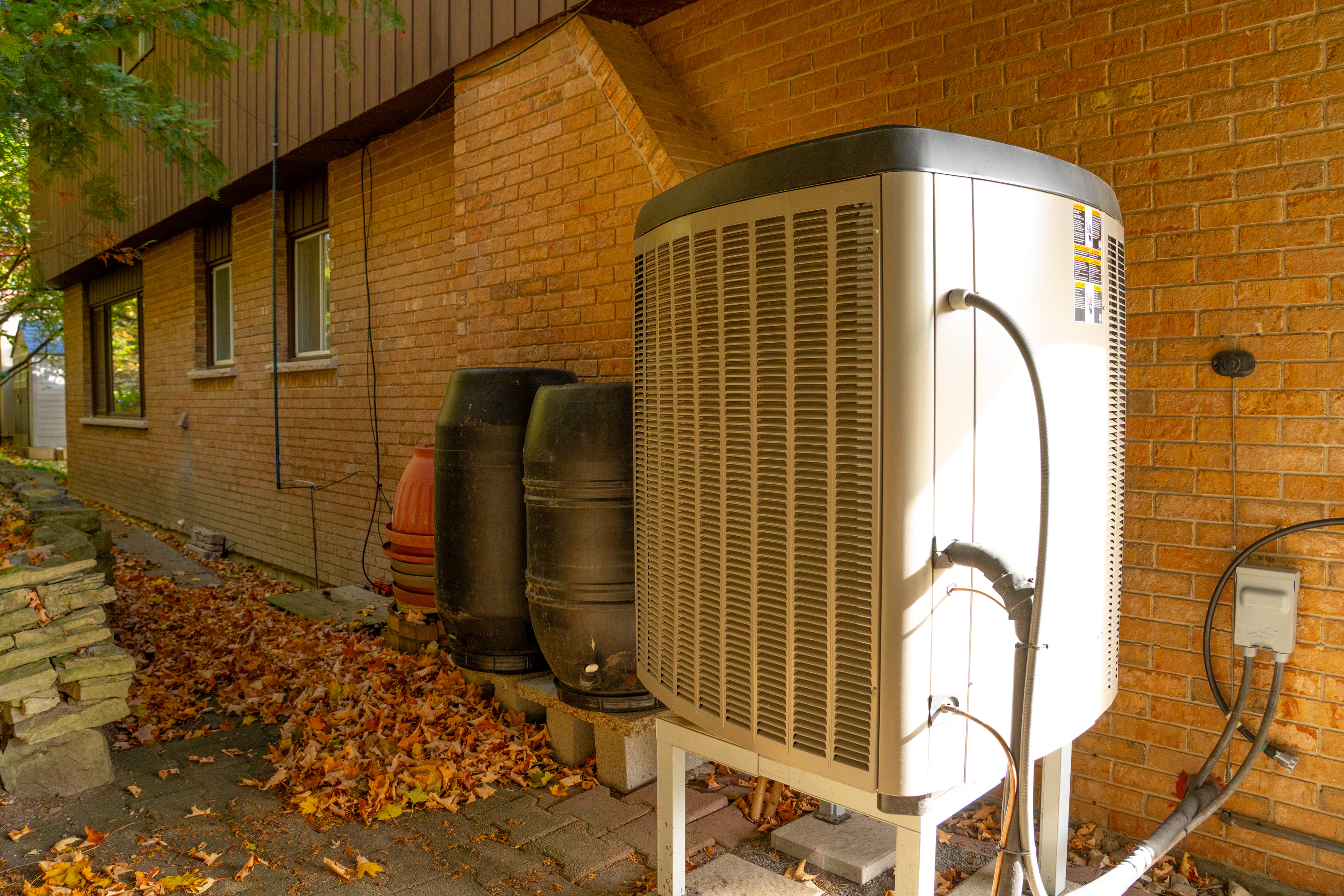 Side view of new heat pump installed in a brick house.