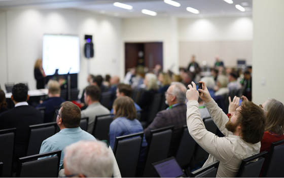 Participantes et participants prenant des photos d’une présentation à un atelier de la Conférence sur les collectivités durables 2025.