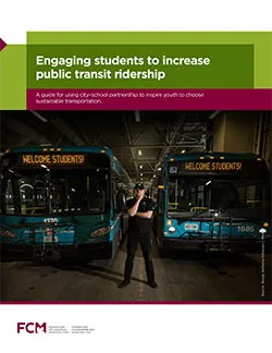 Man standing between two parked buses, the digital signage on bus reads "WELCOME STUDENTS!"