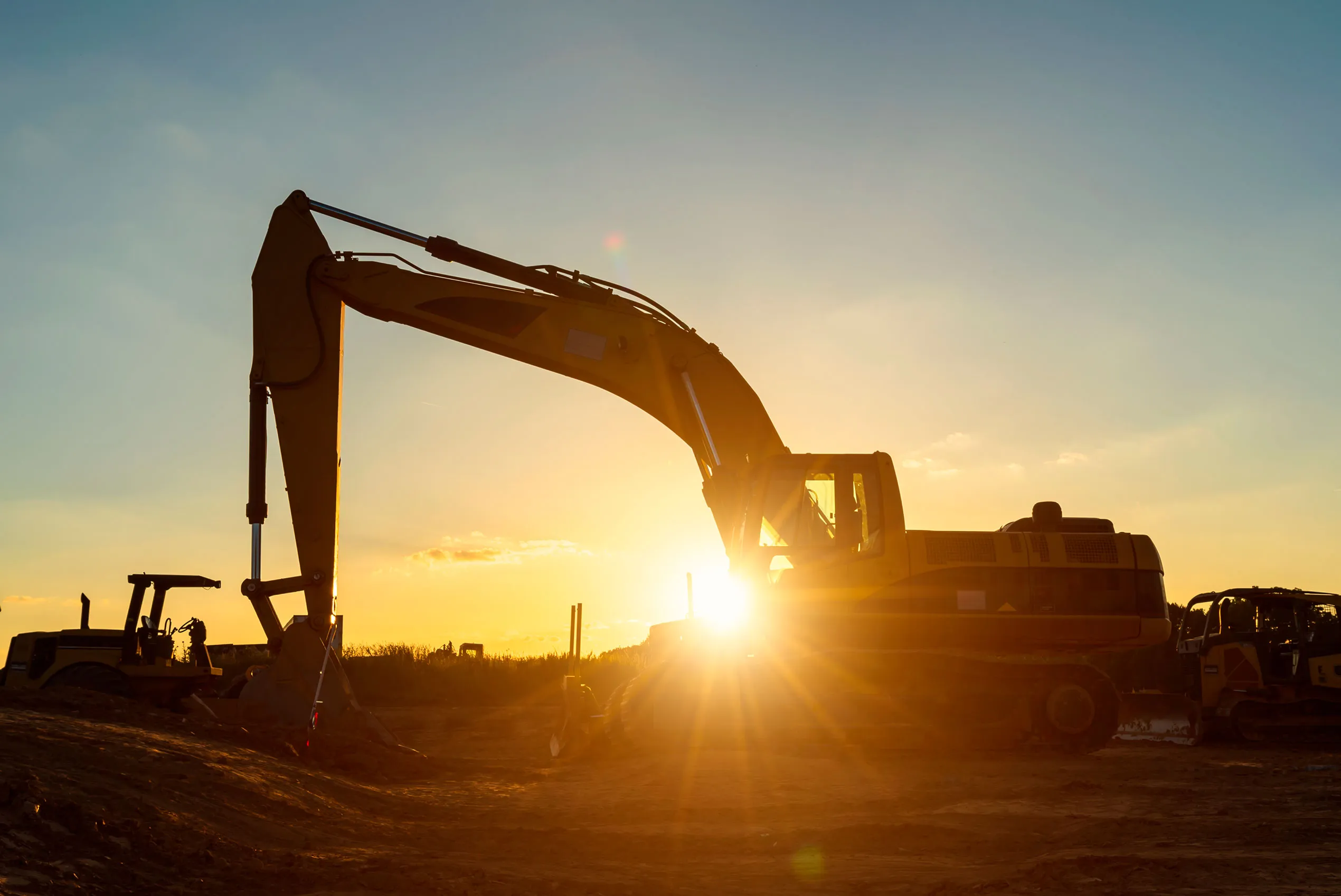 Excavator, bulldozer, and other equipment at construction site at twilight