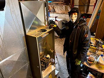 A person wearing a mask standing indoors working on electrical equipment