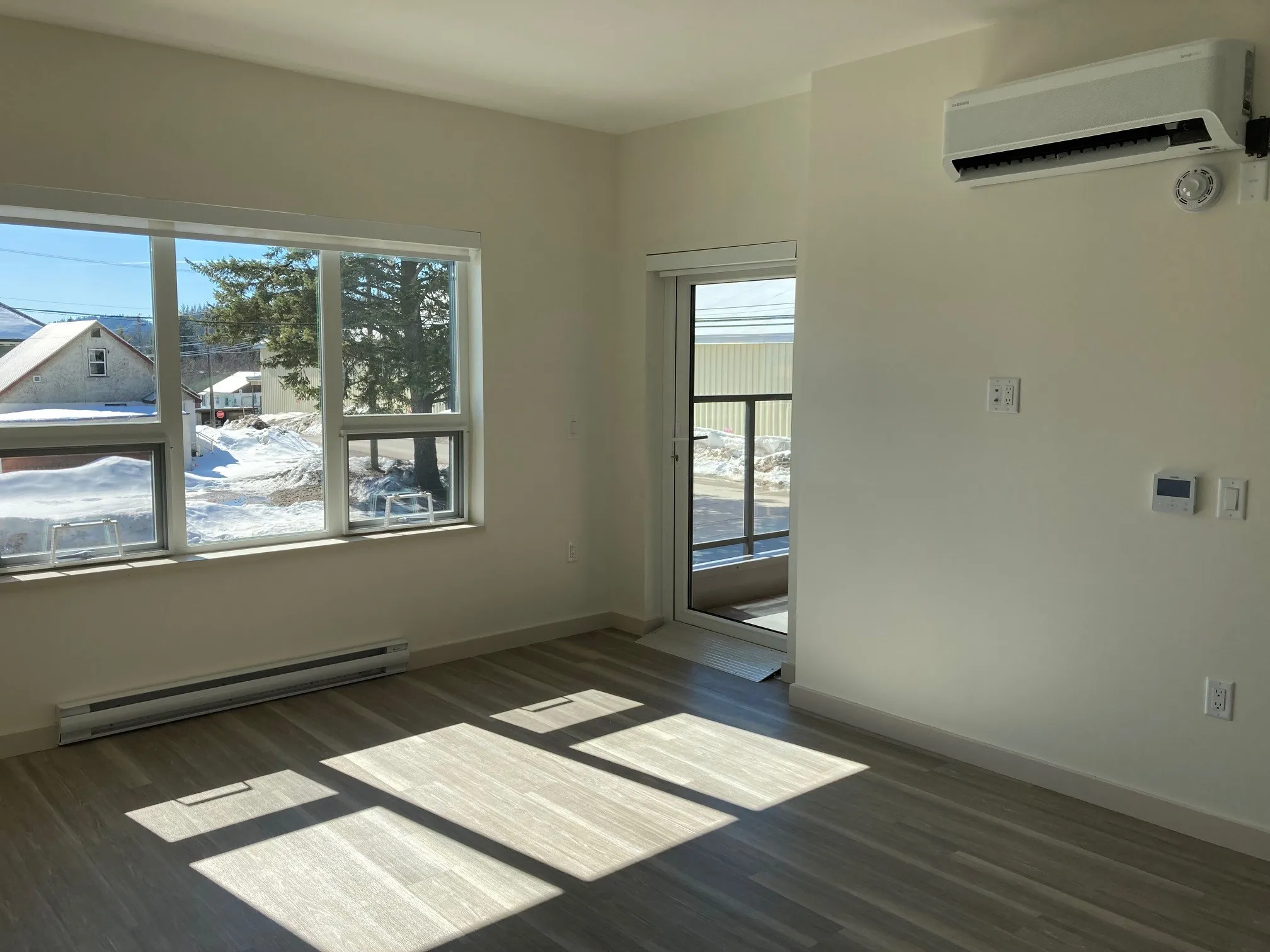An empty living space with windows and a door in the Rossland Yards affordable housing building in Rossland, BC