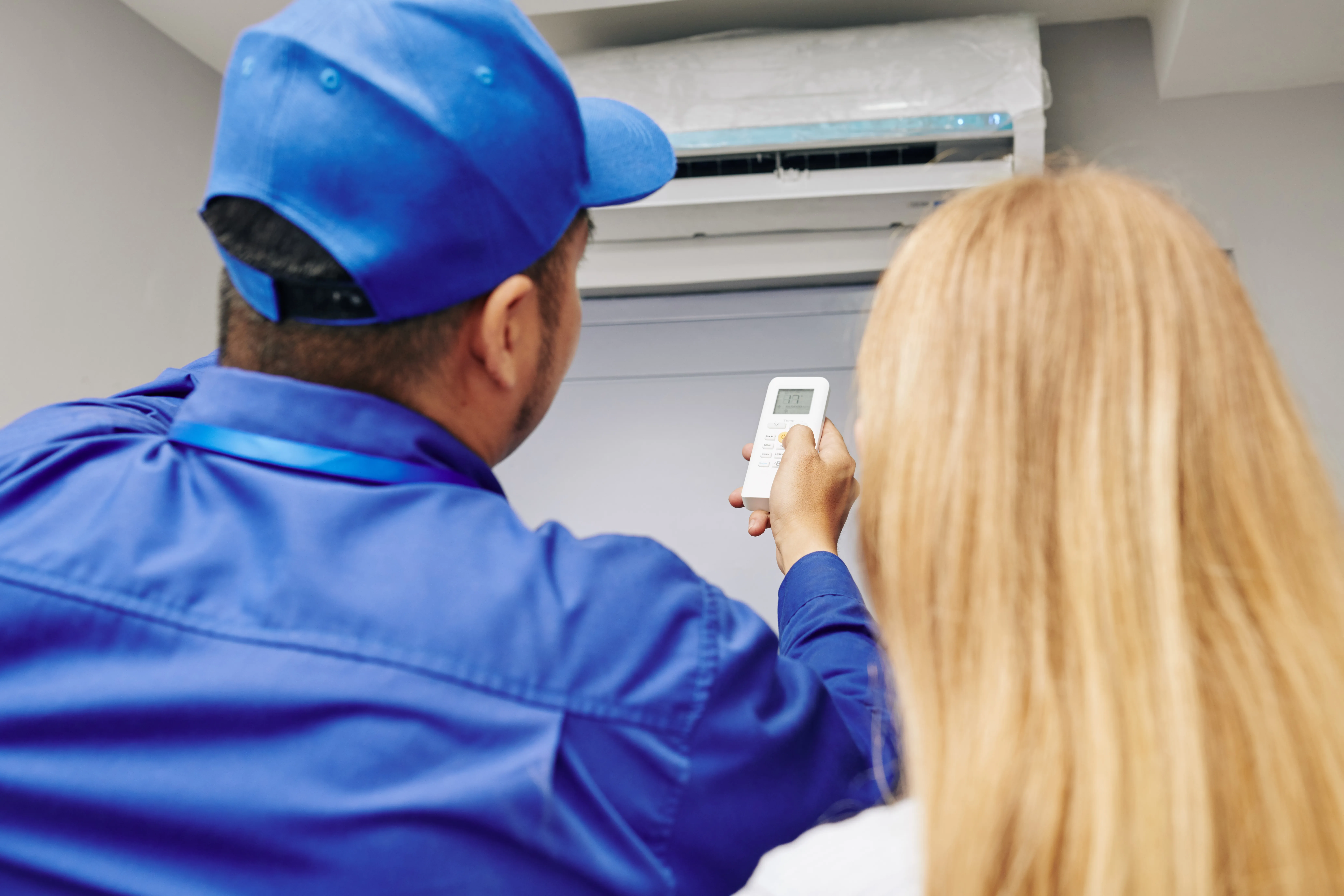 A service worker shows a resident how to use their new air conditioner