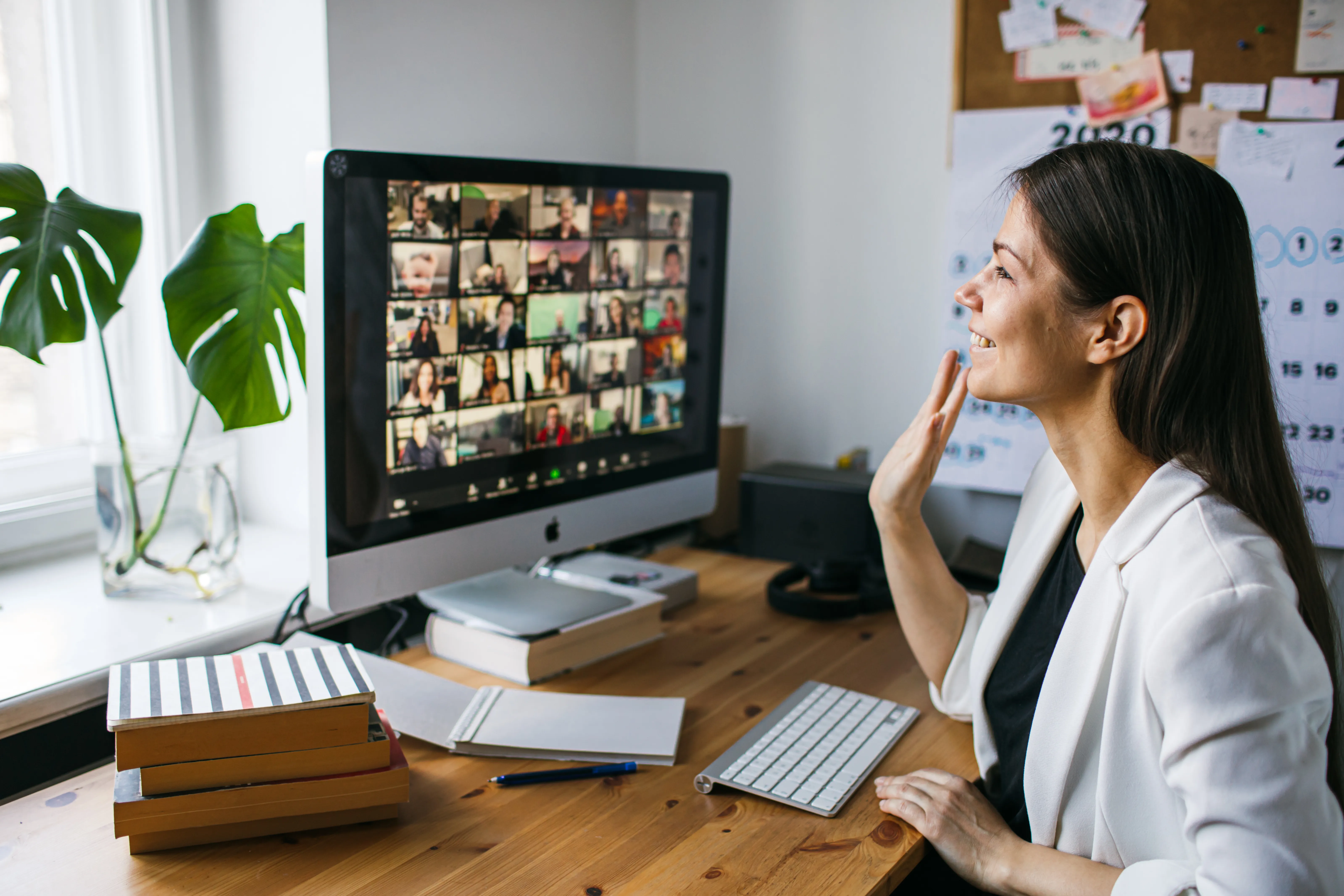 A professional woman waving to colleagues during a virtual meeting, symbolizing connection and collaboration in an inclusive setting. 