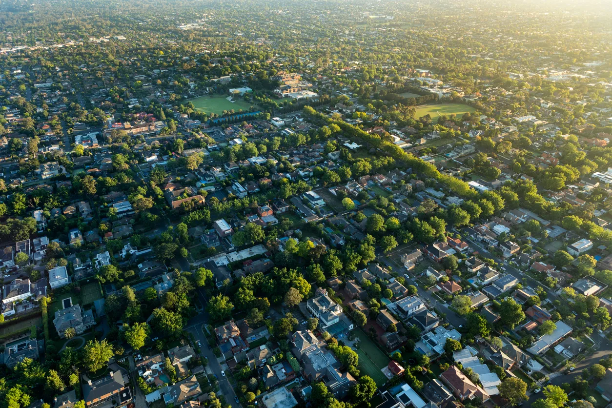 An aerial view of a neighbourhood surrounded with trees during sunrise.
