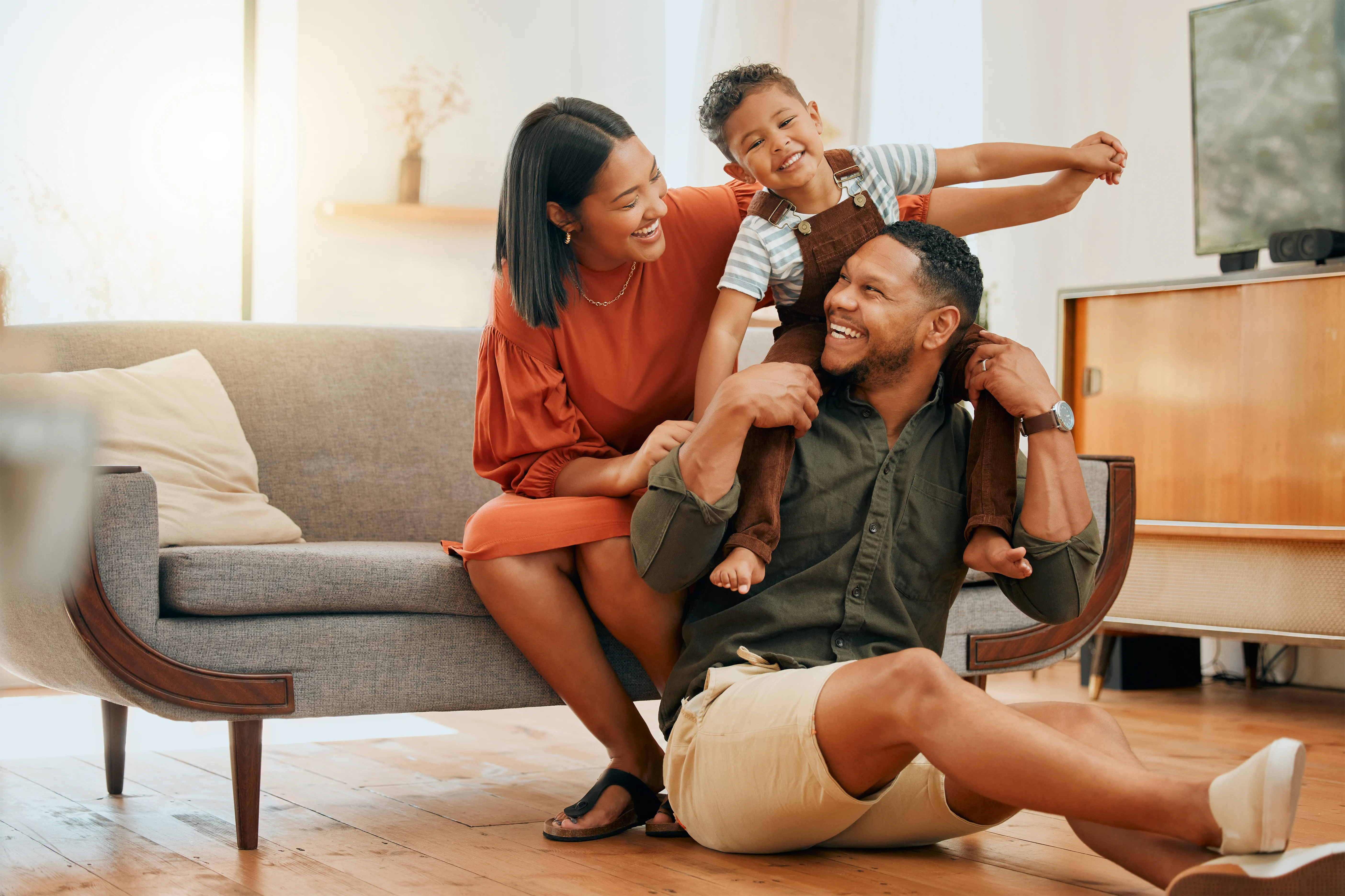 A happy family of three relaxing in their living room and playing together. 