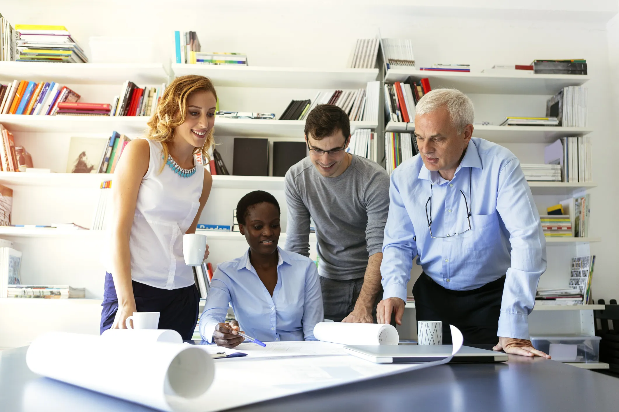 Diverse group of professionals collaborating around a table, reviewing large-format plans and discussing strategies, representing municipal climate governance and planning. 