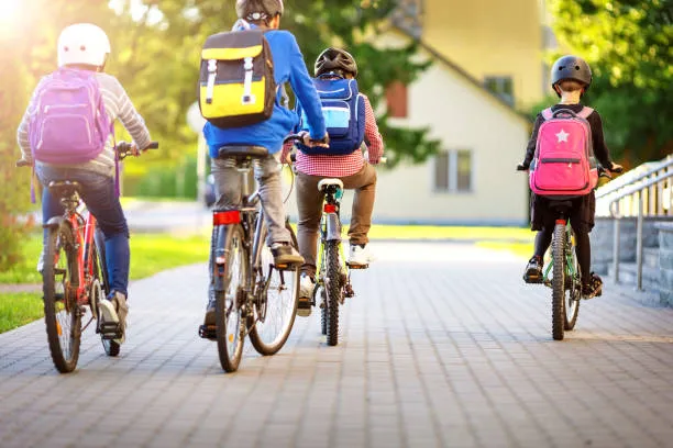 Students with backpacks biking to school on a sunny day
