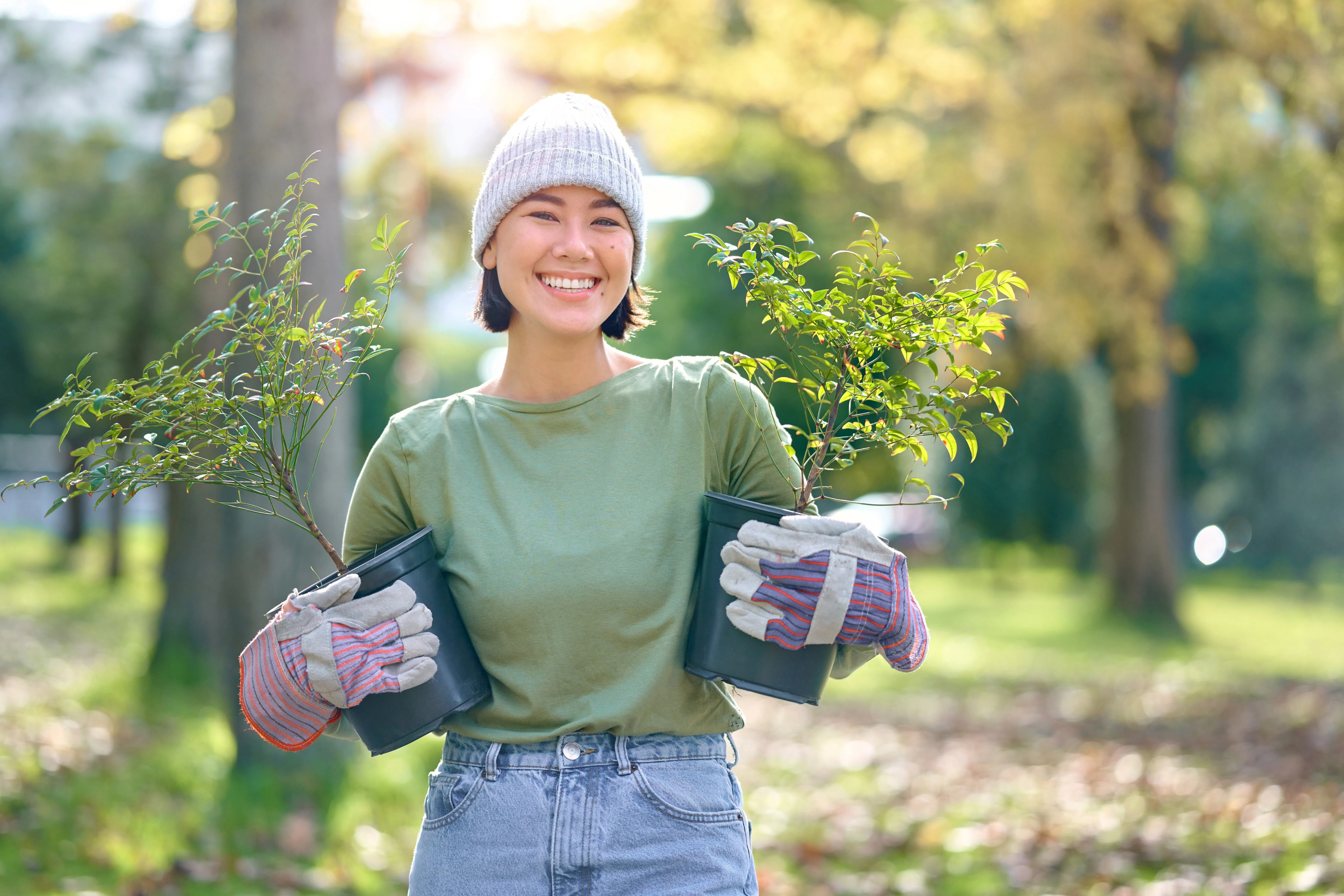 A community member holds two potted trees at a planting site