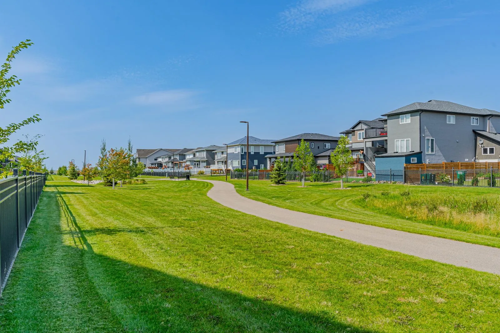 A ground-level view of the Aspen Heights complex, showing multiple rows of blue and white townhomes, surrounded by greenery and walkways