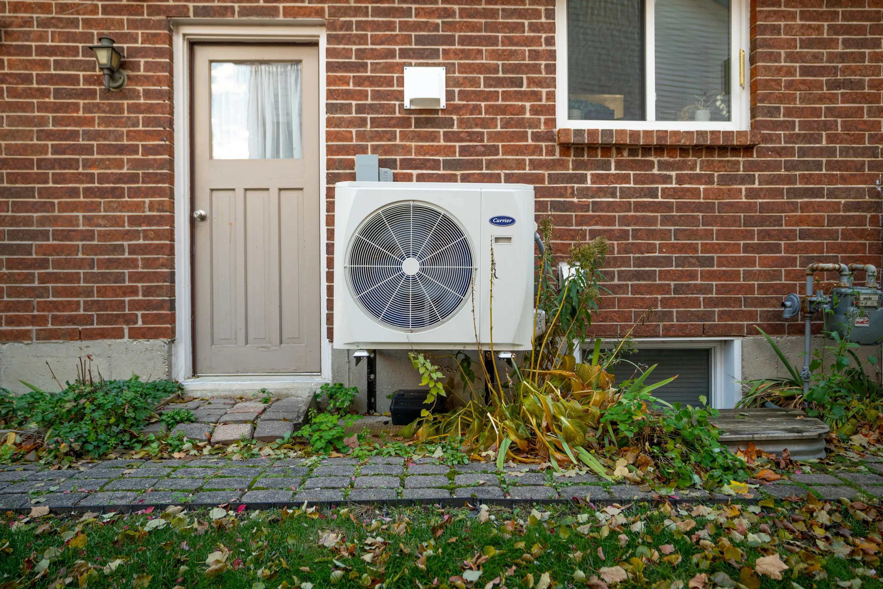 Newly installed heat pump on the side of a brick house. 