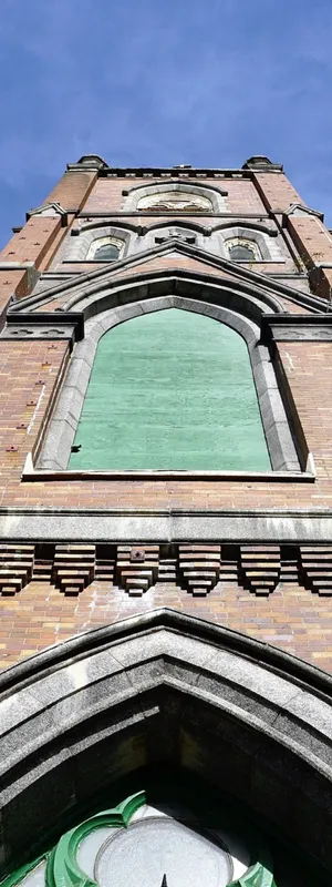 Skyward view of an ornate red brick community building against a bright blue sky with slight white clouds. 