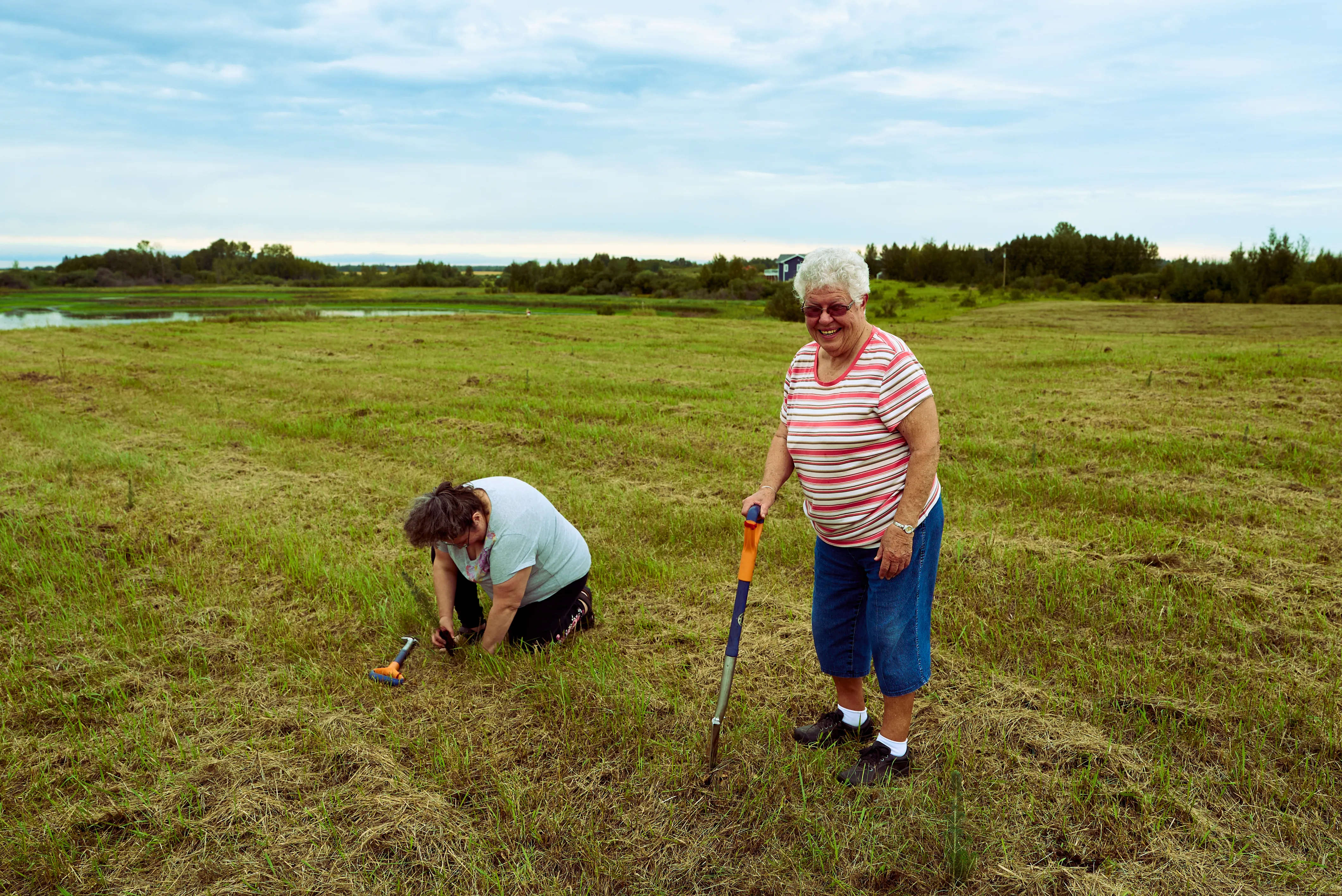 Two community members planting seedlings on empty land.